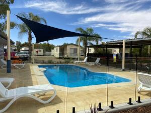 a swimming pool with a large umbrella over it at Broken Hill Tourist Park in Broken Hill