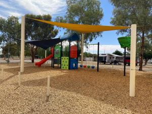 un parque infantil con tobogán y columpio en Broken Hill Tourist Park, en Broken Hill