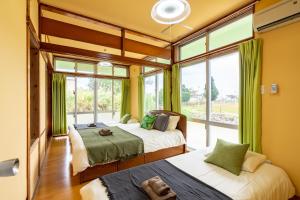 2 camas en una habitación con ventanas grandes en Deluxe Room 130平米 URUMAHOTEL, en Uruma