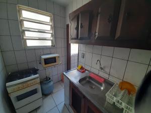 uma pequena cozinha com um lavatório e um micro-ondas em Apartamento mobiliado no Canto do Forte - Praia Grande - SP Férias, temporada, feriados em São Paulo