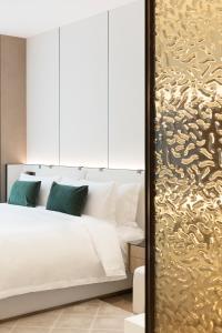 Shenzhen Ayearn Hotel في شنجن: غرفة نوم بسرير ابيض وجدار ذهبي