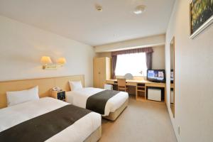 a hotel room with two beds and a television at Yamagata Kokusai Hotel in Yamagata