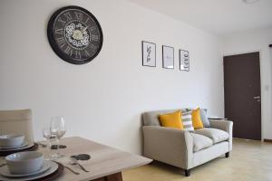 Una sala de estar con un sofá y un reloj en la pared. en En Origen, en Guaymallén