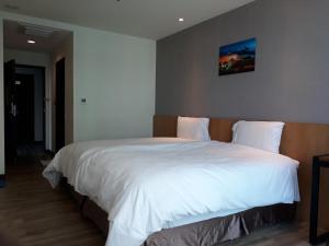 1 dormitorio con 1 cama blanca grande con una foto en la pared en Honest & Warm Hotel, en Taoyuan
