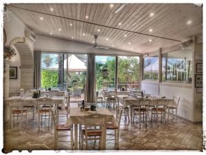 a restaurant with white tables and chairs and windows at Agriturismo La Fattoria in Otranto