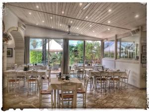 un ristorante con tavoli e sedie bianchi e finestre di Agriturismo La Fattoria a Otranto