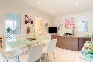 sala de estar con mesa de cristal y sillas blancas en Sydney Executive Garden Apartments, en Engadine