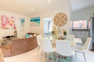 comedor con mesa de cristal y sillas blancas en Sydney Executive Garden Apartments, en Engadine