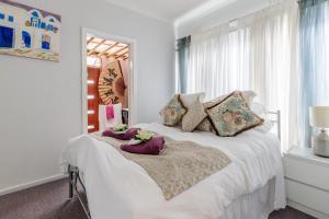 Un dormitorio con una cama blanca con zapatos morados. en Sydney Executive Garden Apartments, en Engadine