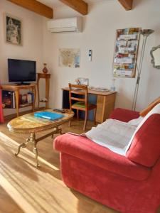 ein Wohnzimmer mit einem roten Sofa und einem Couchtisch in der Unterkunft Studio agréable et très lumineux (Salles d'Aude) in Salles-dʼAude