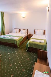 a hotel room with two beds and a table at Pensiunea 3 Brazi Zarnesti in Zărneşti