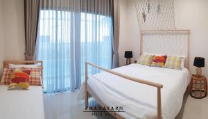 a bedroom with a bed and a large window at Pranatarn Pool Villa Endless Summer in Pran Buri