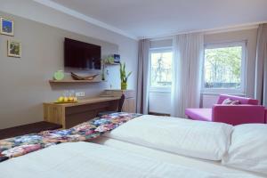 a hotel room with two beds and a pink chair at Landgasthof Apfelblüte garni in Salem