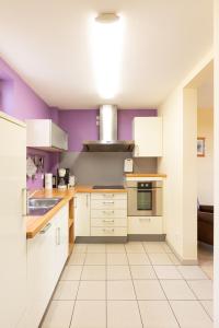 a kitchen with white cabinets and purple walls at Schäfer's Ferienhof Michaelsberg in Gundelsheim