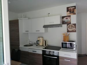 a kitchen with white cabinets and a sink and a microwave at Strandläufer in Gelbensande