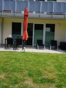 an orange umbrella sitting on a lawn in front of a house at Strandläufer in Gelbensande