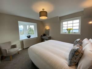 a bedroom with a bed and a chair and two windows at The Inn At Charlestown in Dunfermline