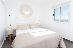 biała sypialnia z dużym łóżkiem i lustrem w obiekcie Higuerón Rental Marítimo Romar D w mieście Fuengirola