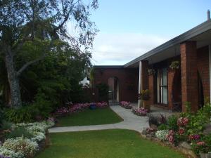 una casa con un jardín de flores en el patio en Havenlee Homestay, en Westport