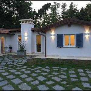 una casa bianca con finestre con persiane blu e un patio di Il Gioiello B&B a Marina di Pietrasanta