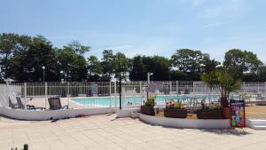 a swimming pool with chairs and plants in a park at Normandie Sword Beach in Hermanville-sur-Mer