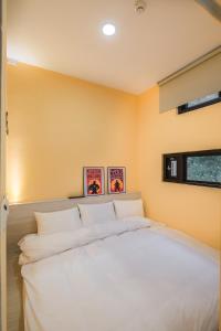 a large white bed in a room with yellow walls at 貓頭鷹旅店 in Yuchi