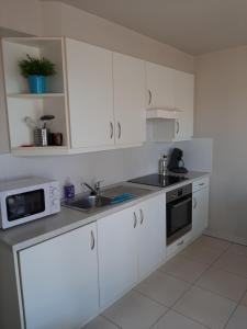 a kitchen with white cabinets and a sink and a microwave at Appartement vlakbij zee en duinen in Bredene