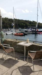a table and two chairs next to a marina with boats at Reed's of Fowey in Fowey
