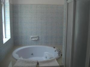 een badkamer met een bad en blauwe tegels bij WelcomHeritage Fernhills Royal Palace in Ooty
