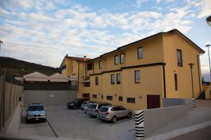 un bâtiment jaune avec des voitures garées dans un parking dans l'établissement Felix Hotel, à Montecchio Maggiore