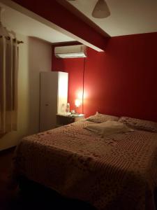 a bedroom with a red wall with a bed at QUARTO Jardim da Serra in Nova Petrópolis