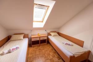 Duas camas num pequeno quarto com uma janela em Apartment Stella em Dolenjske Toplice