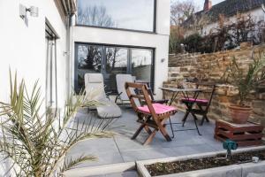 un patio con sillas, una mesa y una pared de piedra en Neu gebautes Apartment mit Sonnenterasse in der Nähe vom Siebengebirge & Bonn en Königswinter
