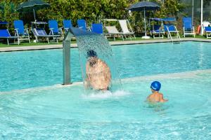 two people playing in a swimming pool at Centro Vacanze Camping Spinnaker in Marina Palmense