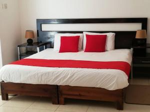 um quarto com uma cama grande e almofadas vermelhas em Mashusha Guest House em Bokaa