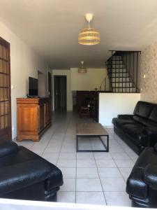 a living room with black leather couches and a table at Gîte des Alondrons in Lissey