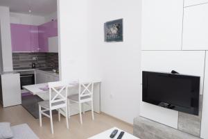 a white kitchen with a table and a tv at Apartman Ladybug in Banja Luka