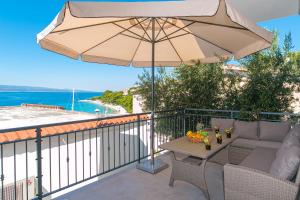 eine Terrasse mit einem Tisch und einem Sonnenschirm in der Unterkunft Brela: Villa Punta in Brela