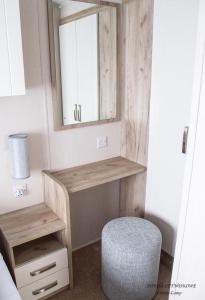 a bathroom with a vanity with a mirror and a stool at Domki Center- Camp in Jarosławiec