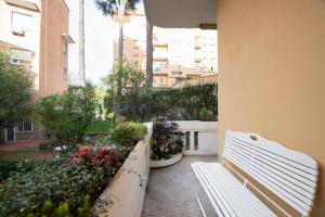 un banco blanco sentado en un balcón con flores en Maison et studio l'Orangerie en Roma