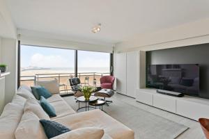 een woonkamer met een grote bank en een tv bij Sunny and comfortable 2 bedroom appartement with stunning Sea-view and 2 terraces in Knokke-Heist
