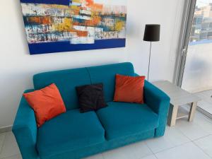 梅利哈的住宿－Sea View Penthouse Mellieha Bay，一张带两个枕头的蓝色沙发以及绘画作品