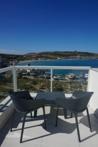 een patio met 2 stoelen en een tafel op een balkon bij Sea View Penthouse Mellieha Bay in Mellieħa