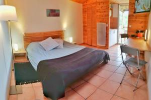 a bedroom with a bed and a desk and a kitchen at Studio 22 m2, terrasse vue lac, dans propriété face au Lac du Salagou in Liausson