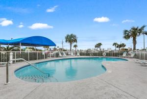 uma piscina com um guarda-sol azul e palmeiras em Island Sunrise 360 em Gulf Shores