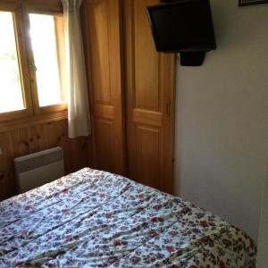 1 dormitorio con 1 cama con manta de flores y TV en Manon, en Hauteluce