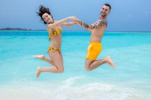 two people jumping in the water on the beach at PERLA Dhangethi in Dhangethi