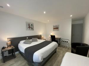 a hotel room with a large bed and a desk at Logis Hôtel L'Oliveraie in Cognac +53 photos