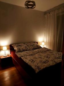 a bedroom with a bed and two lamps on two tables at Apartament Wybrzeze in Gdańsk