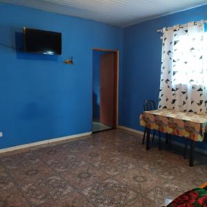 a blue room with a table and a television on a wall at Quarto Duplo Confort in Barueri